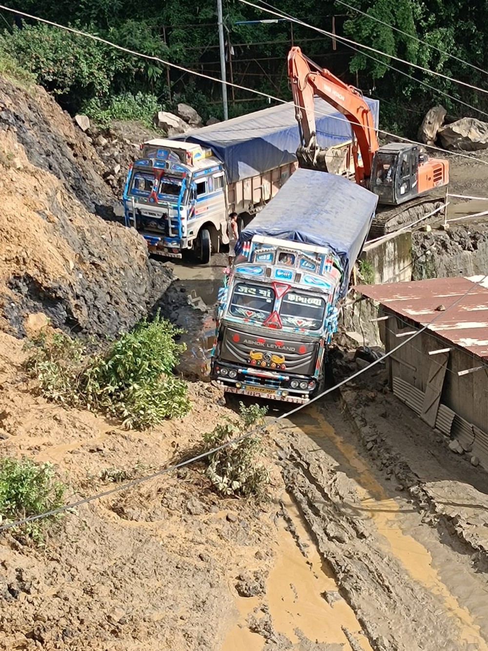 A Manipur-bound stranded truck being rescued with an excavator from a mudslide near the CRPF camp in Lerie Colony, Kohima on June 23. (Morung Photo)